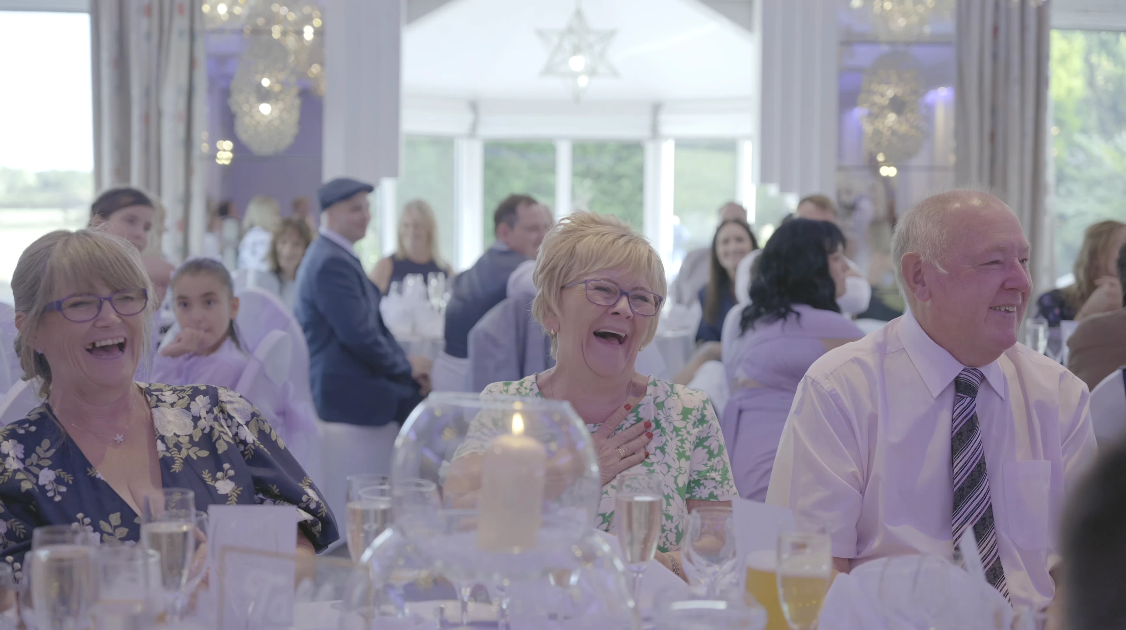Wedding guests laughing together during a reception at Thornton Hall on the Wirral